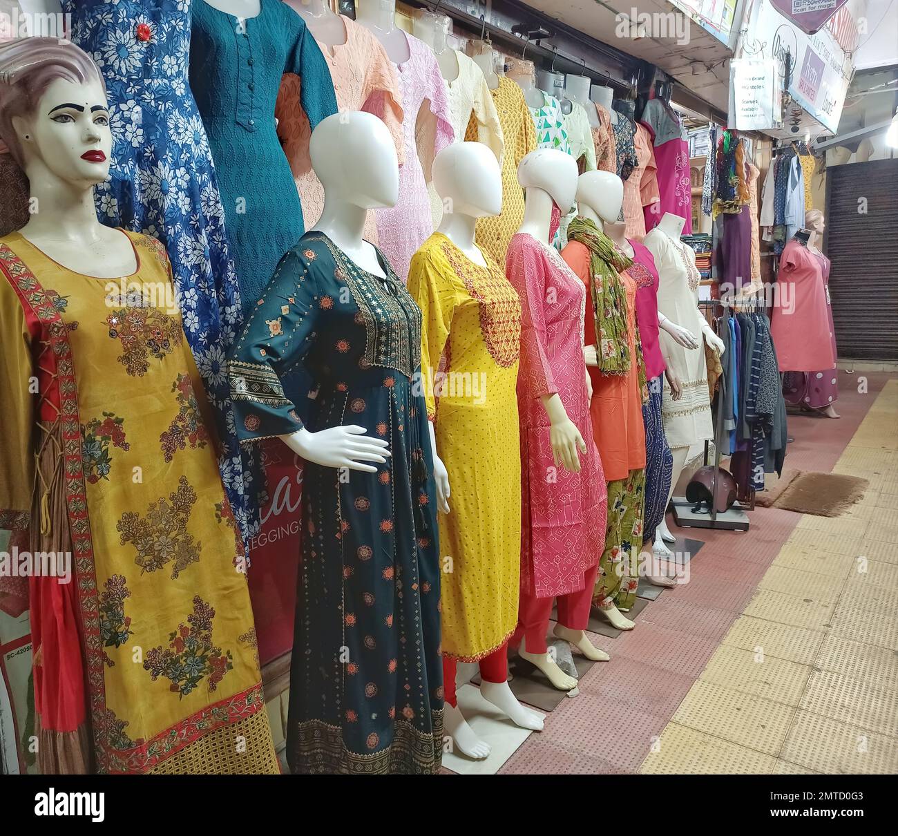 A row of female mannequins wearing traditional clothing placed in a shopping complex in India