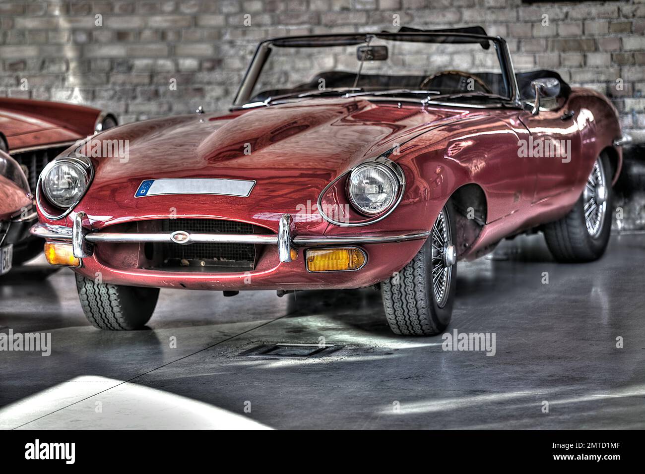 A Jaguar E-Type Convertible HDR Red parked in a garage Stock Photo