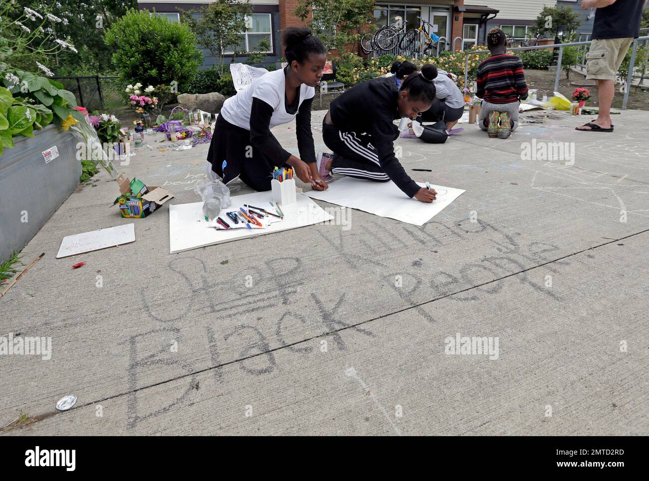 Qrenesia McClendon, left, and Kissehanet Tesfa make signs at a memorial outside where a pregnant mother was shot and killed at her apartment a day earlier by police, Monday, June 19, 2017, in Seattle. Family members of Charleena Lyles questioned Monday why police didn't use a Taser or other non-lethal options when they encountered the woman, who the officers knew had been struggling with mental health issues. (AP Photo/Elaine Thompson) Stock Photo
