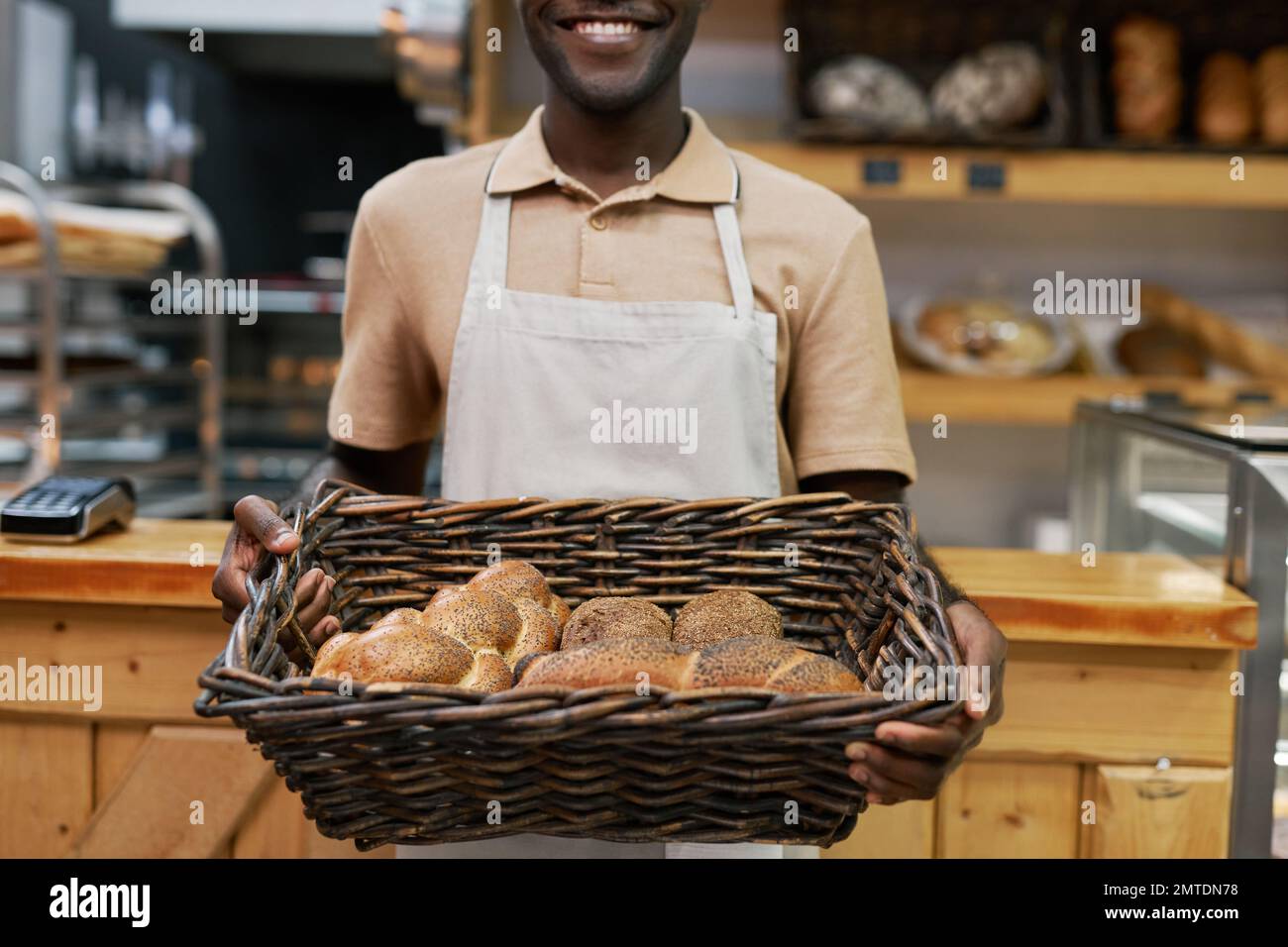 Positive baker holding basket of delicious bread loafs and buns Stock Photo
