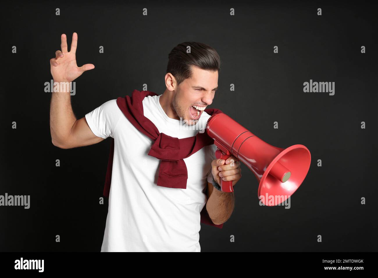 Handsome man with megaphone on black background Stock Photo