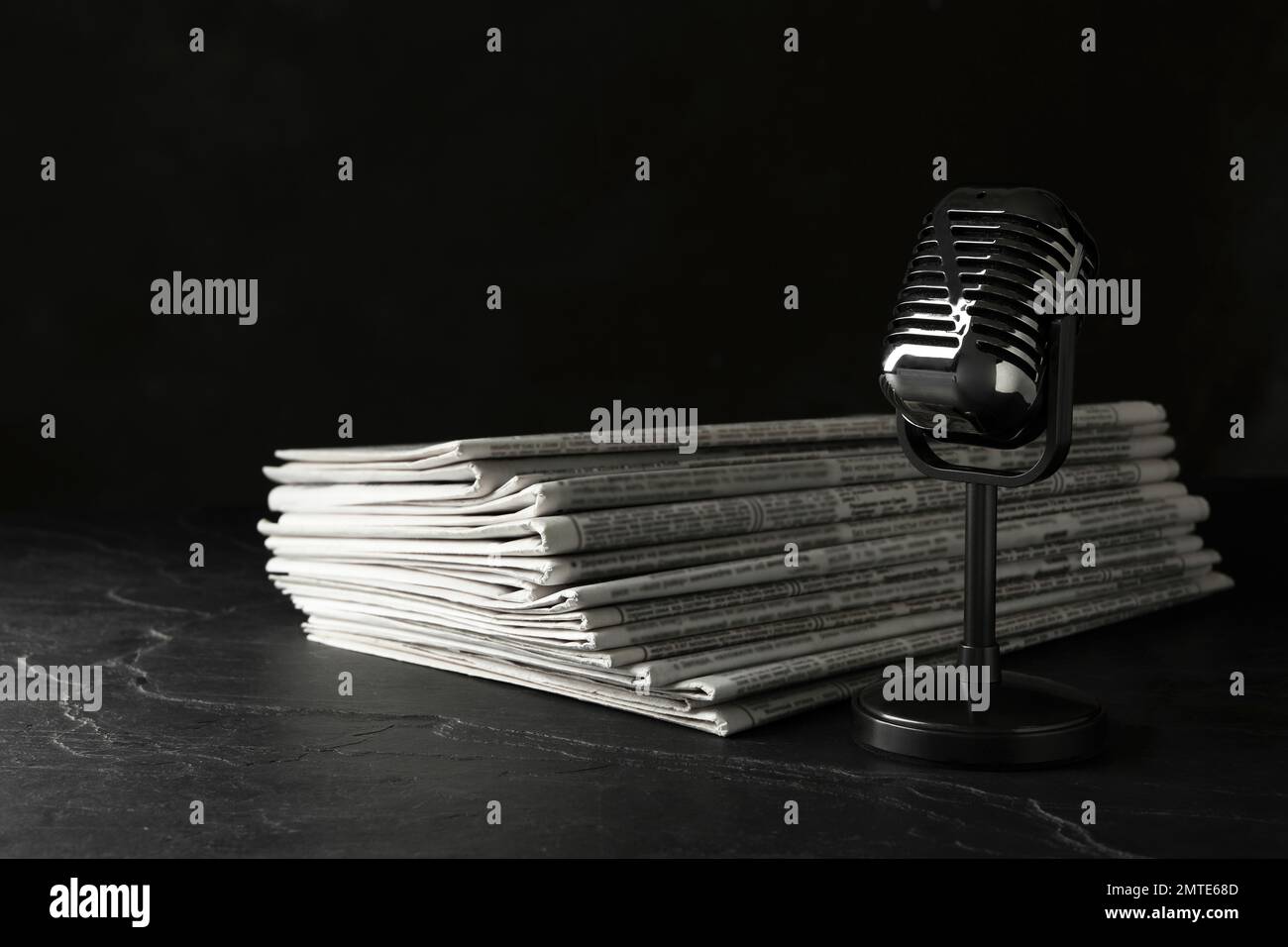 Newspapers and vintage microphone on dark stone table. Journalist's work Stock Photo