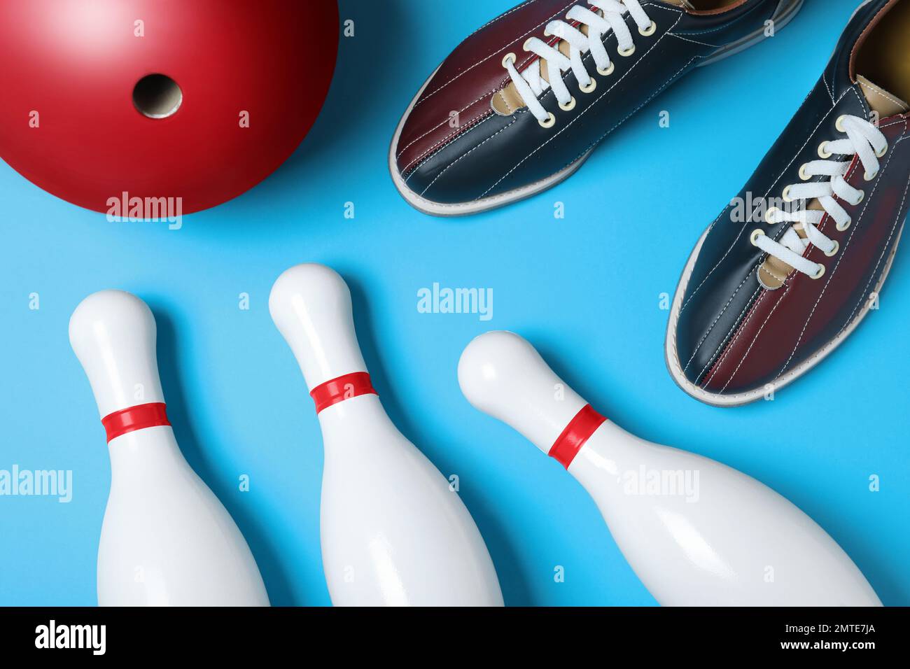 Bowling ball, shoes and pins on light blue background, flat lay Stock Photo
