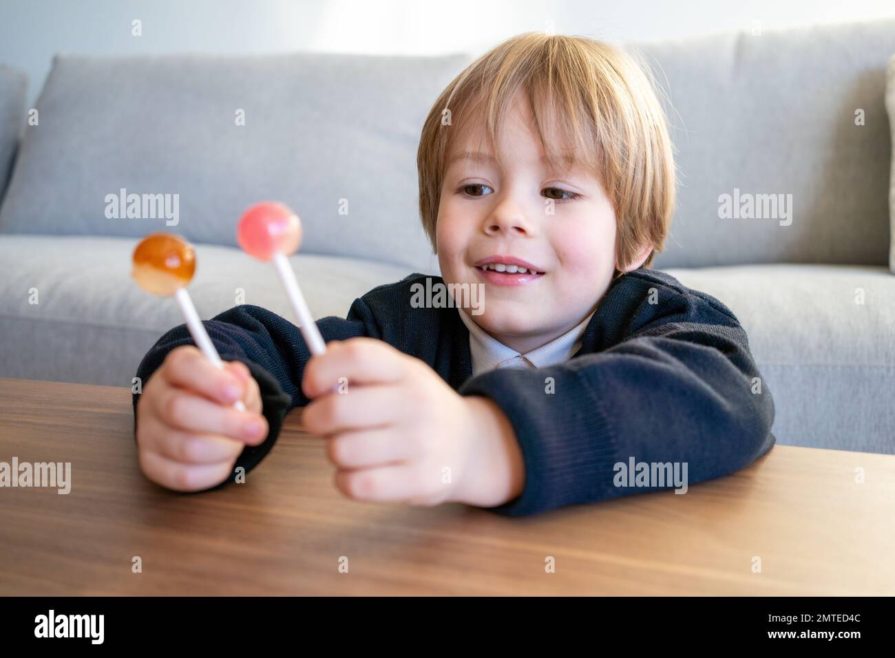 Little toddler child, blond boy, licking lollipop at home Stock Photo