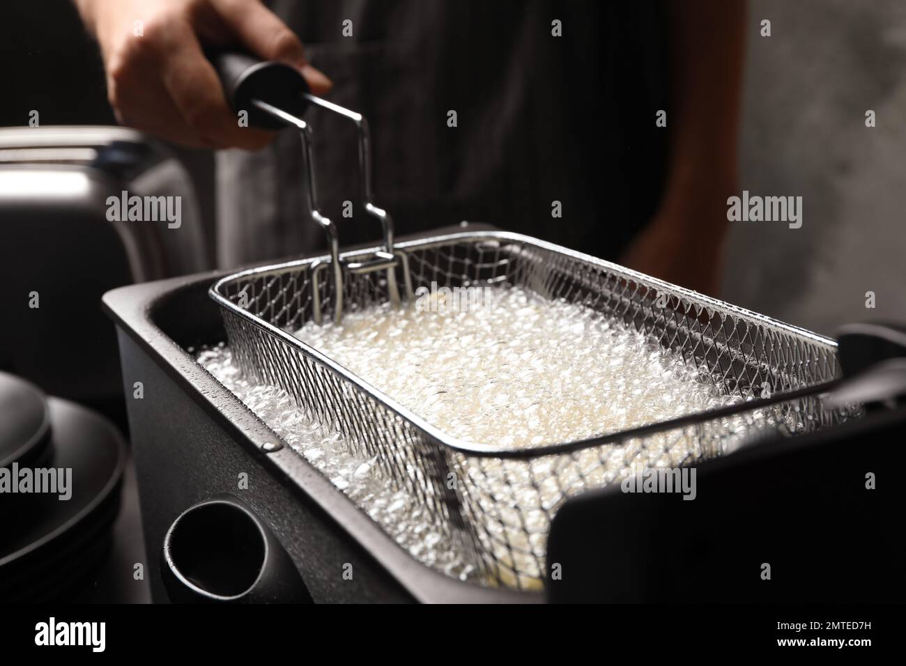 Chef cooking delicious french fries in hot oil, closeup Stock Photo