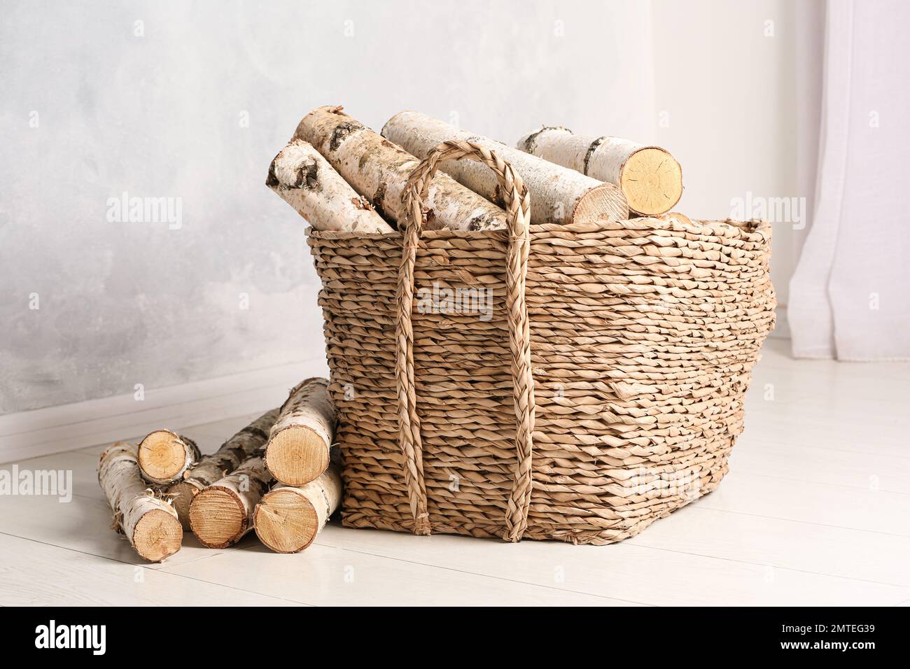 Wicker basket with cut firewood on white floor indoors Stock Photo Alamy