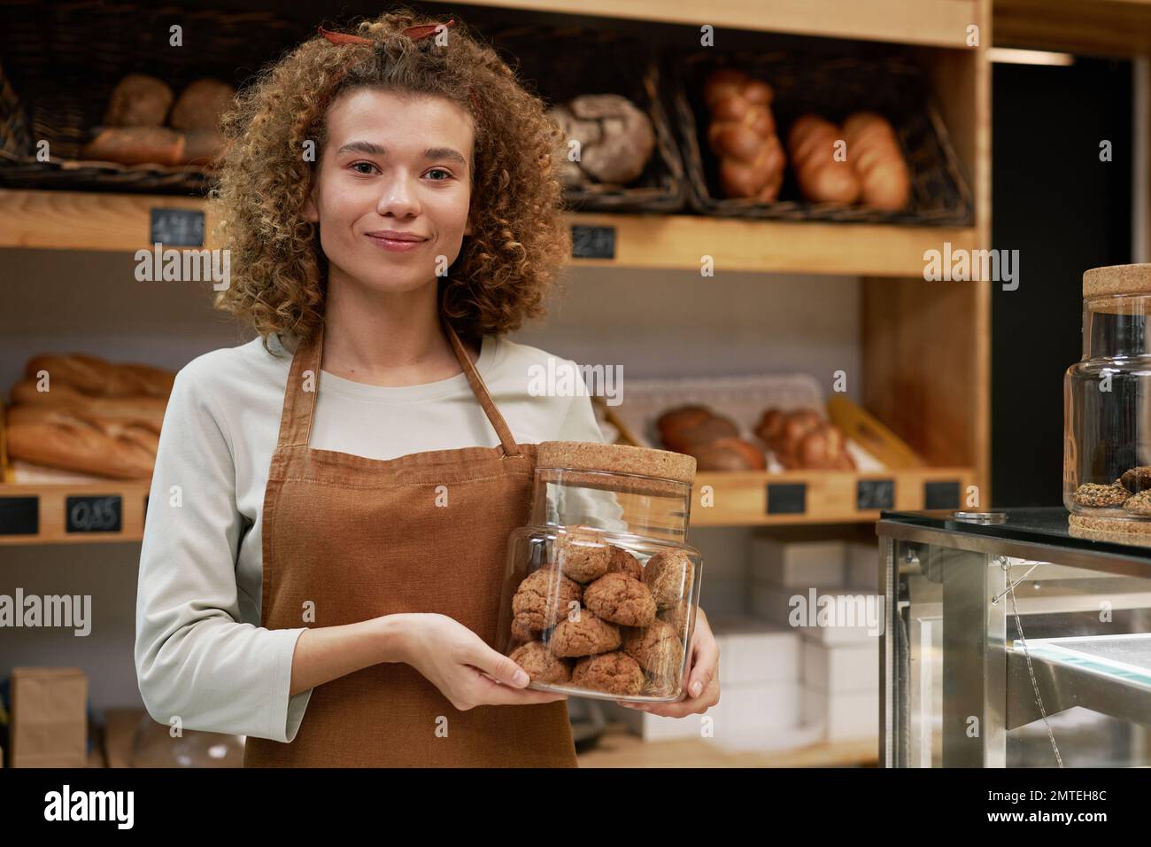 Smiling bakery owner holding jar of gluten free cookies Stock Photo