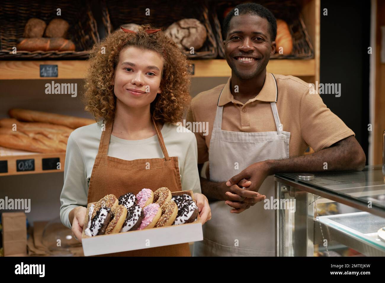 Portrait of happy bakery owners with box of fresh donuts Stock Photo