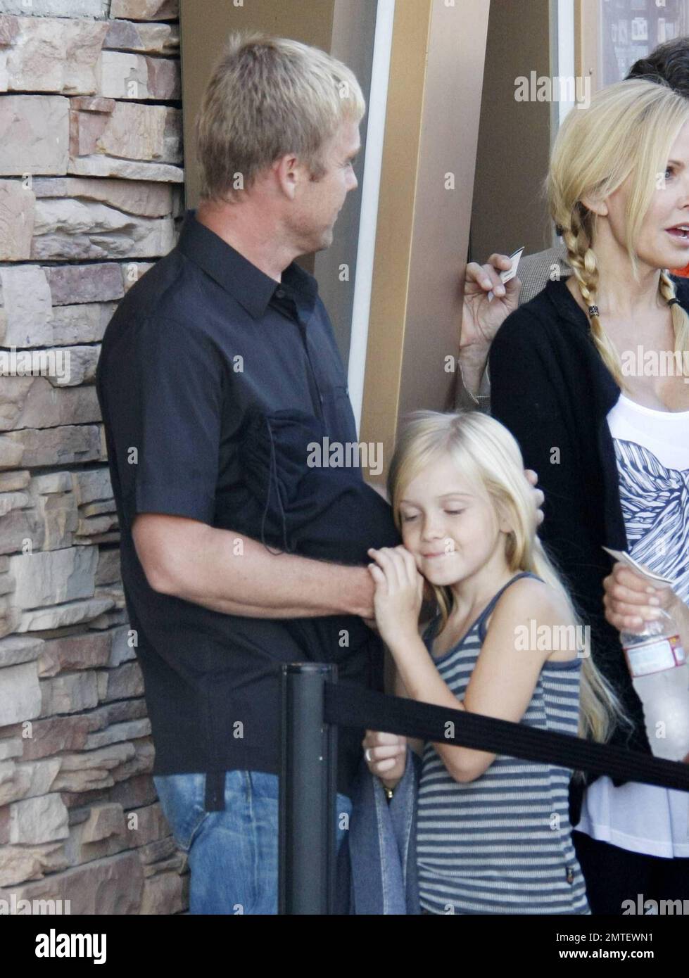 Actor Rick Schroder smiles and laughs with his wife Andrea Schroder and their two daughters Cambrie (pink hoodie) and Faith Anne (brown boots).  The family stood in line at the Malibu Cinema waiting to see a movie. Los Angeles, CA. 07/17/10.   . Stock Photo