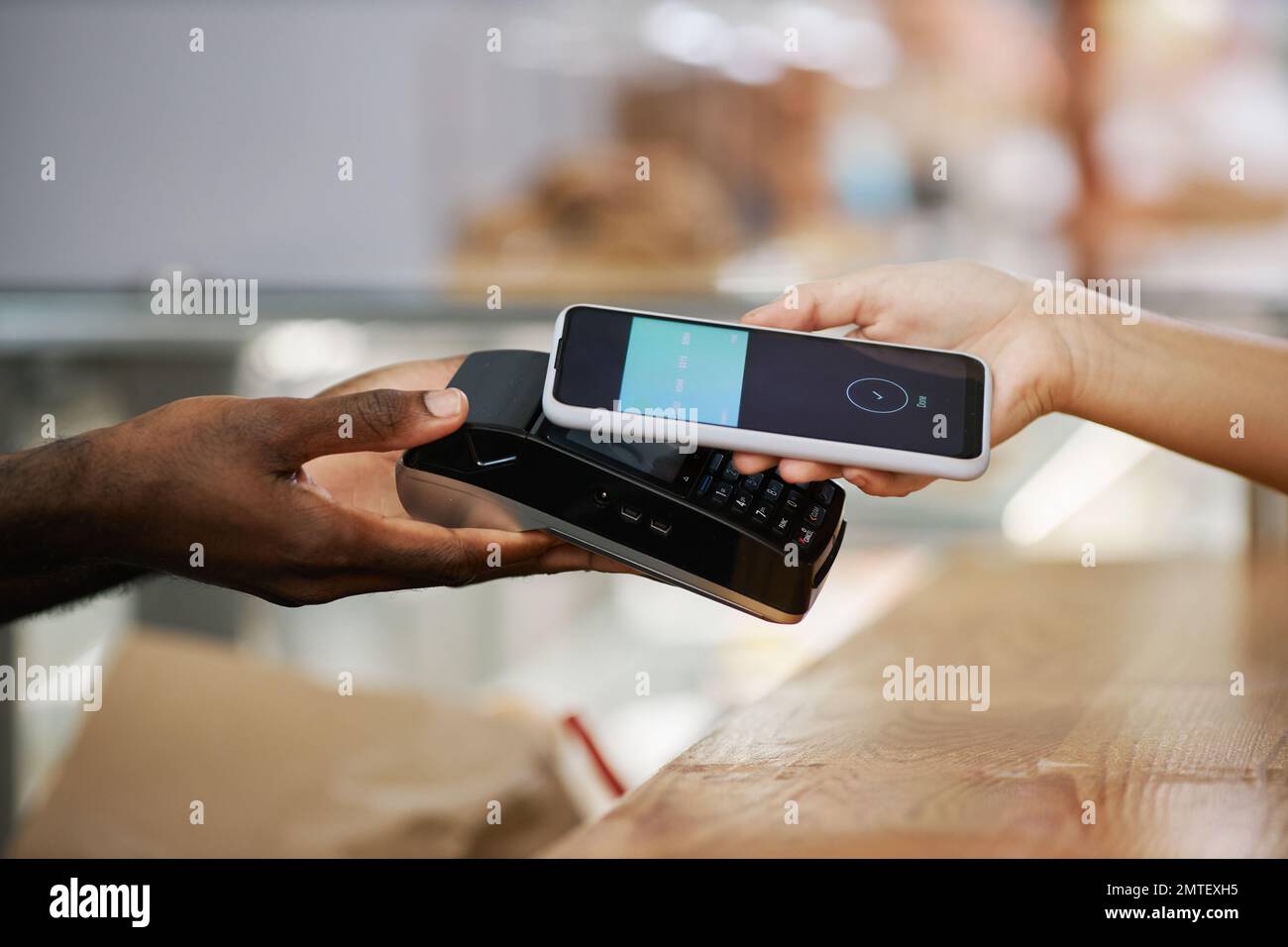 Hand of customer using banking app when paying for purchase in bakery Stock Photo