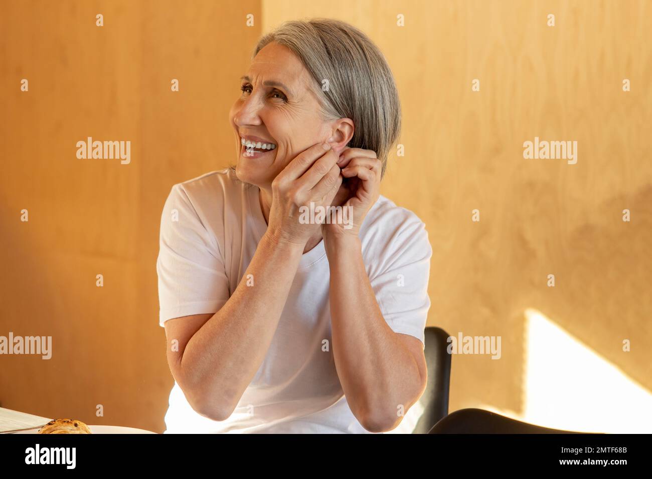 Smiling mid aged woman wearing her earrings Stock Photo
