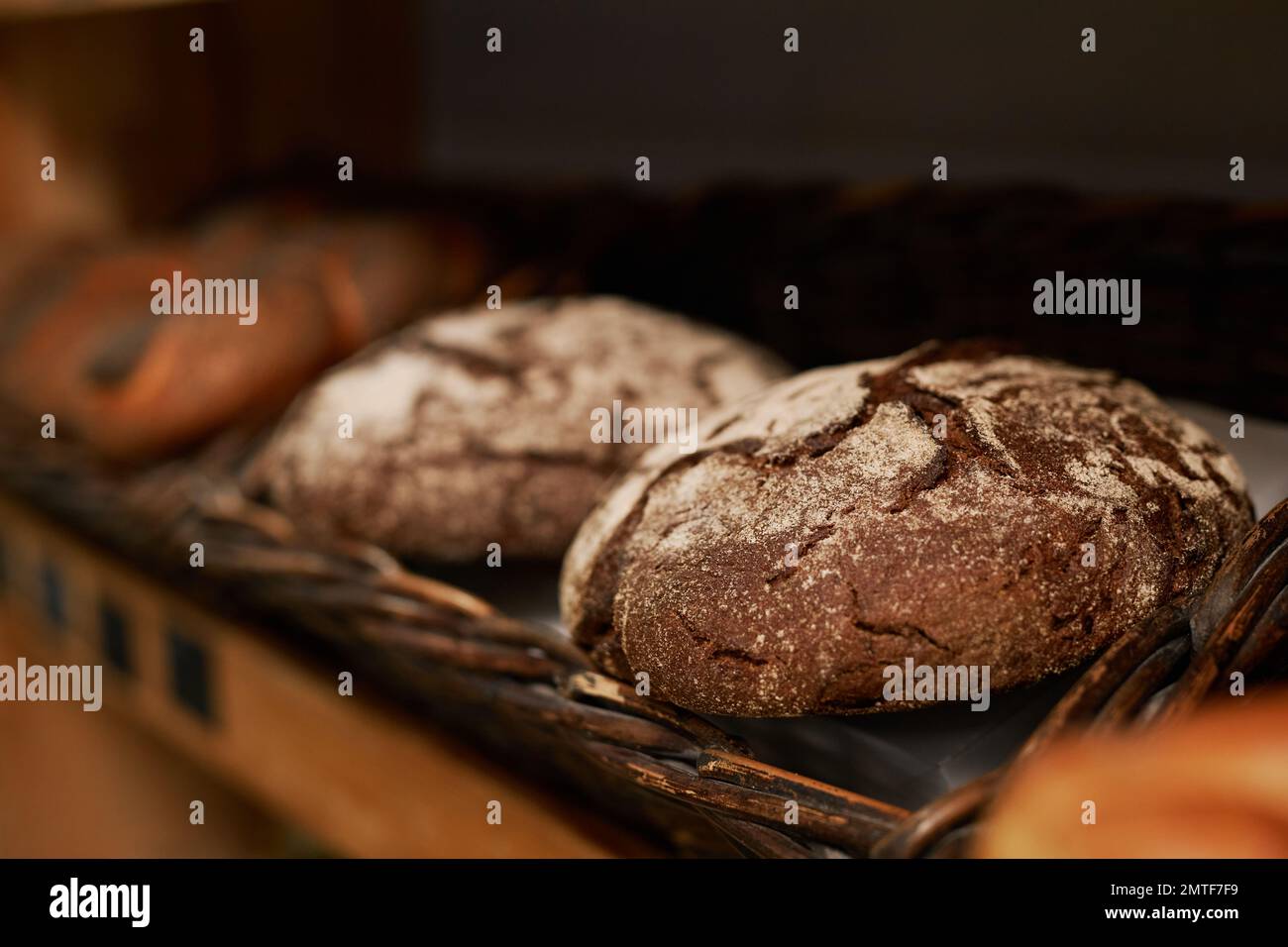Loafs of rye bread on wooden shelves in bakery Stock Photo