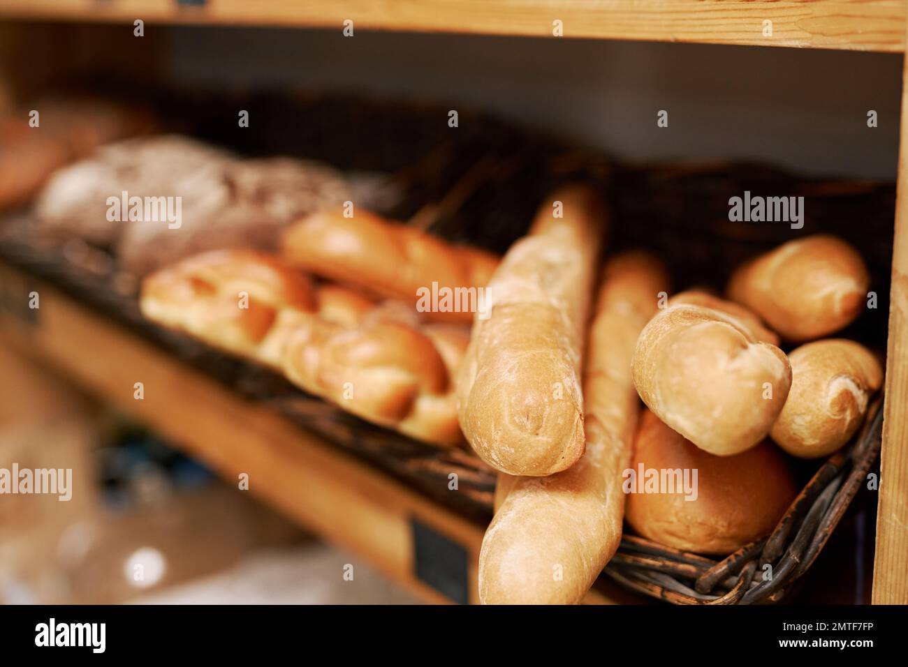 Freshly baked baguettes on shelves in bakery Stock Photo