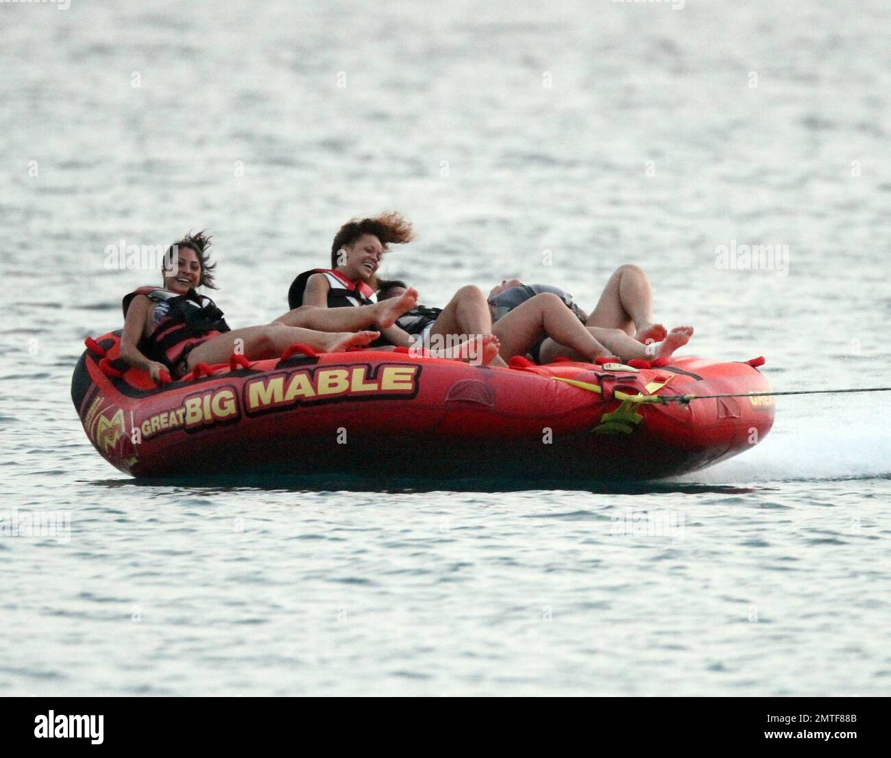 Rihanna can't stop laughing as she enjoys a ride on "Big Mable" with three  pals, who one by one loose grip on the floating bed and get thrown into the  ocean. Attached