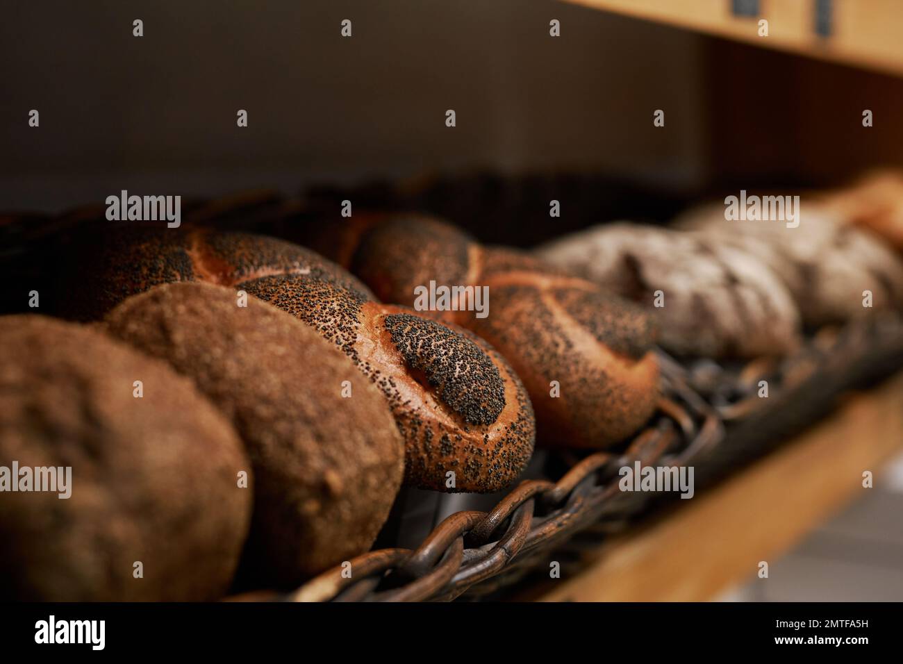 Various types of freshly baked bread on shelves in bakery Stock Photo
