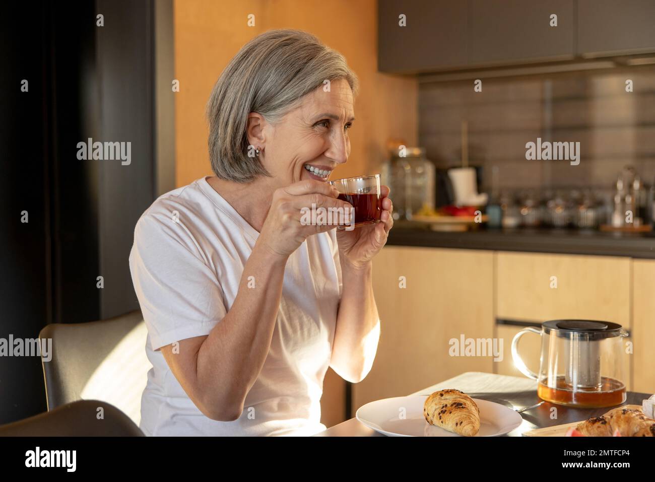 Gray-haired good-looking woman having tea in the morning Stock Photo