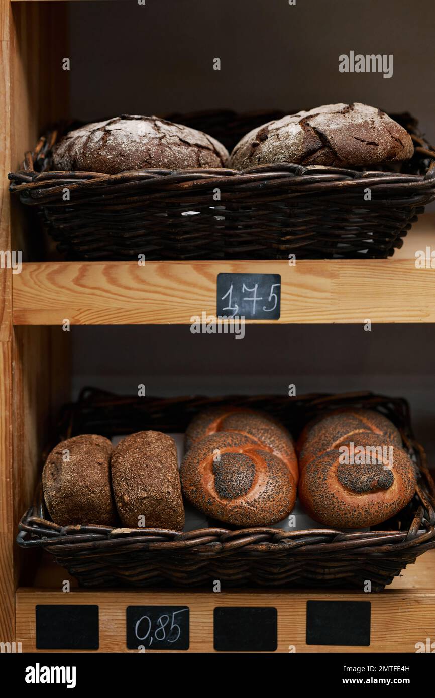 Baskets with rye bread, gluten free loafs and poppy seeds bread on shelves in store Stock Photo