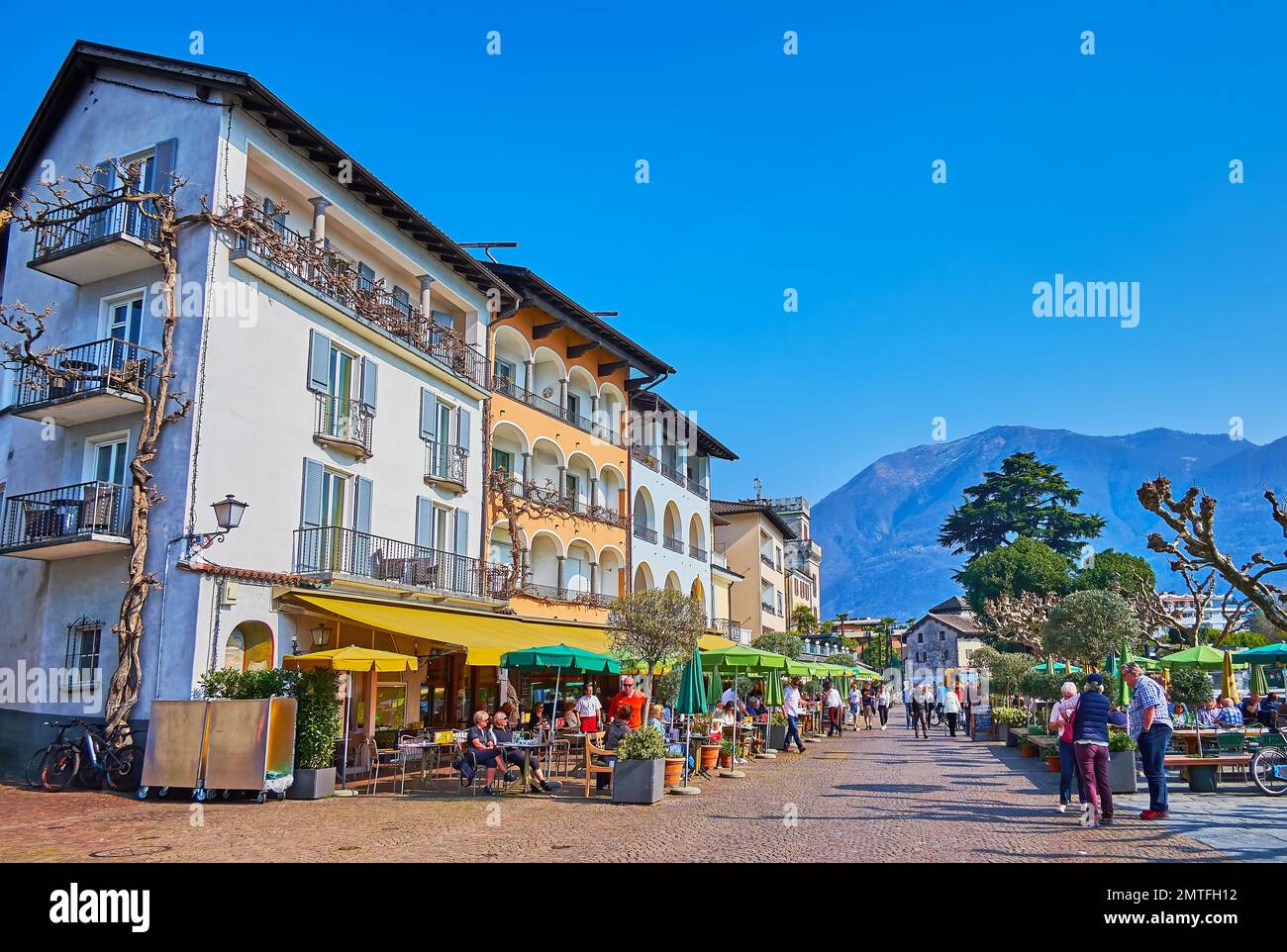 ASCONA, SWITZERLAND - MARCH 28, 2022: The dense housing on Piazza Giuseppe Motta with beautiful terraces, decorated with green plants and flowers in p Stock Photo