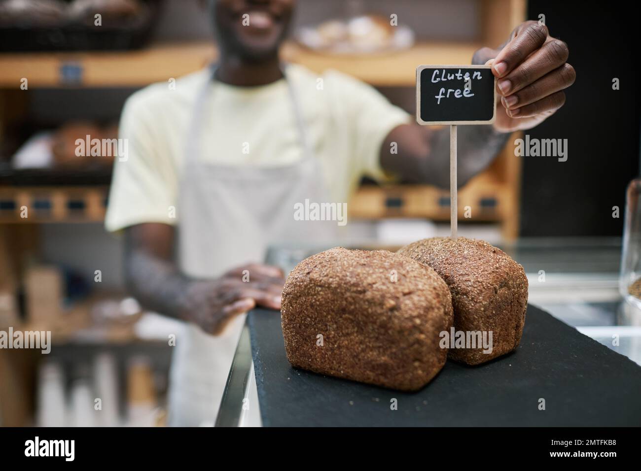 Baker putting gluten-free loafs of bread in store showcase Stock Photo