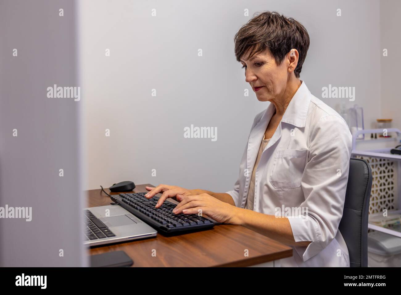Female doctor sitting at the laptop and typing Stock Photo