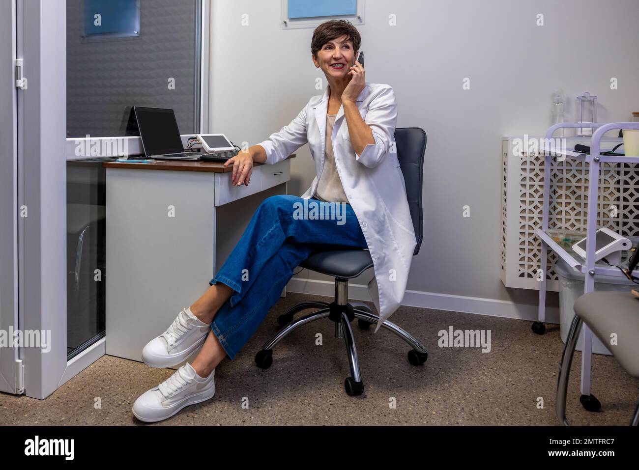 Female doctor sitting at the office and talking on the phone Stock Photo