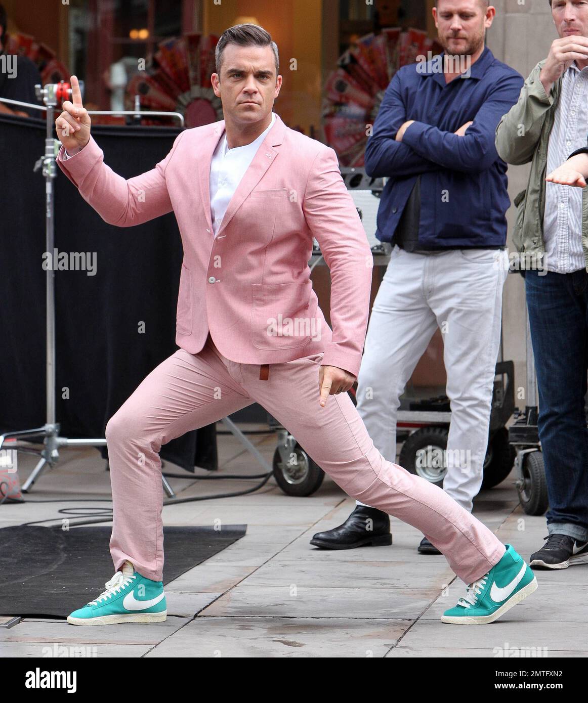 Wearing a pink suit with baby blue Nike sneakers, Robbie Williams and  'Skins' star Kaya Scodelario were spotted on set filming scenes for his new  music video in East London. According to