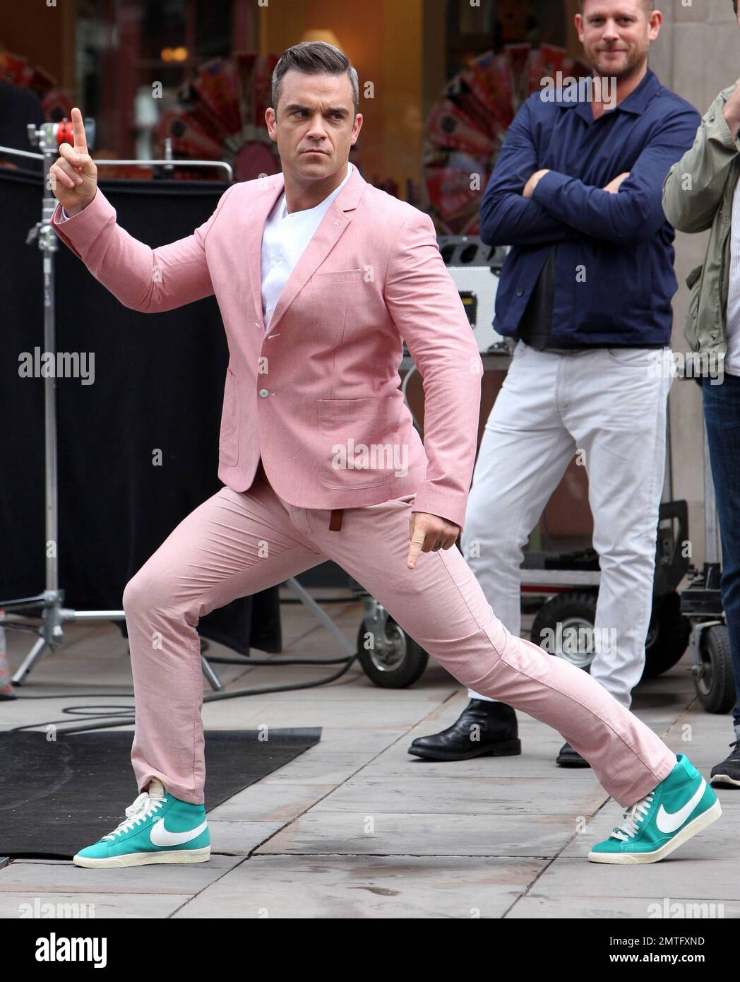 Wearing a pink suit with baby blue sneakers, Robbie Williams and star Kaya Scodelario were spotted on set filming scenes for his new music video in London. According to