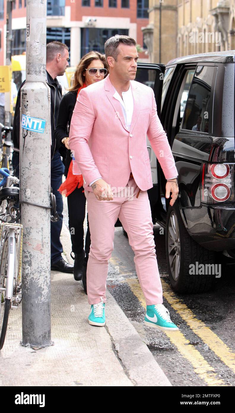 Wearing a pink suit with baby blue sneakers, Robbie Williams and star Kaya Scodelario were spotted on set filming scenes for his new music video in London. According to