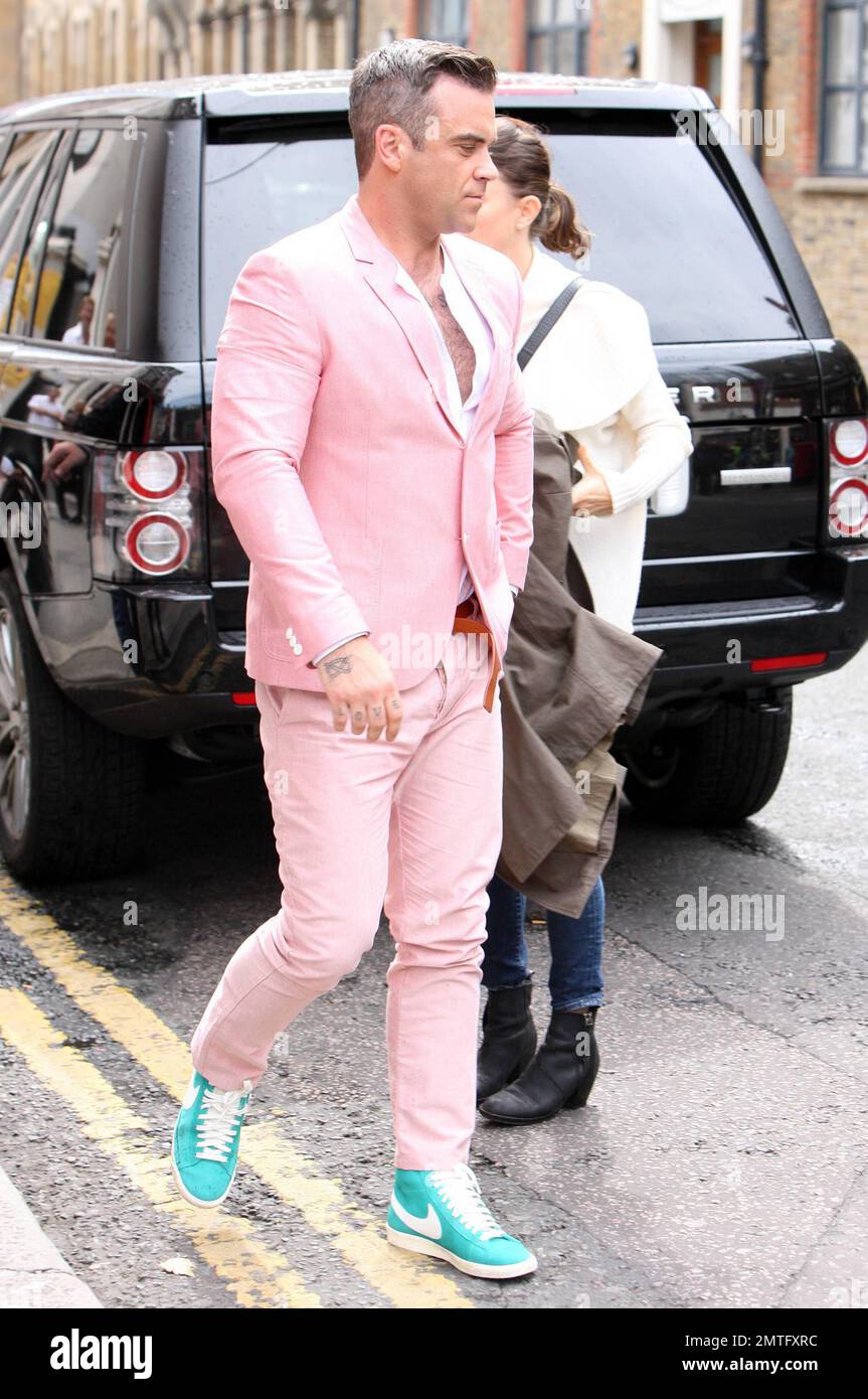 Wearing a pink suit with baby blue Nike sneakers, Robbie Williams and  'Skins' star Kaya Scodelario were spotted on set filming scenes for his new  music video in East London. According to