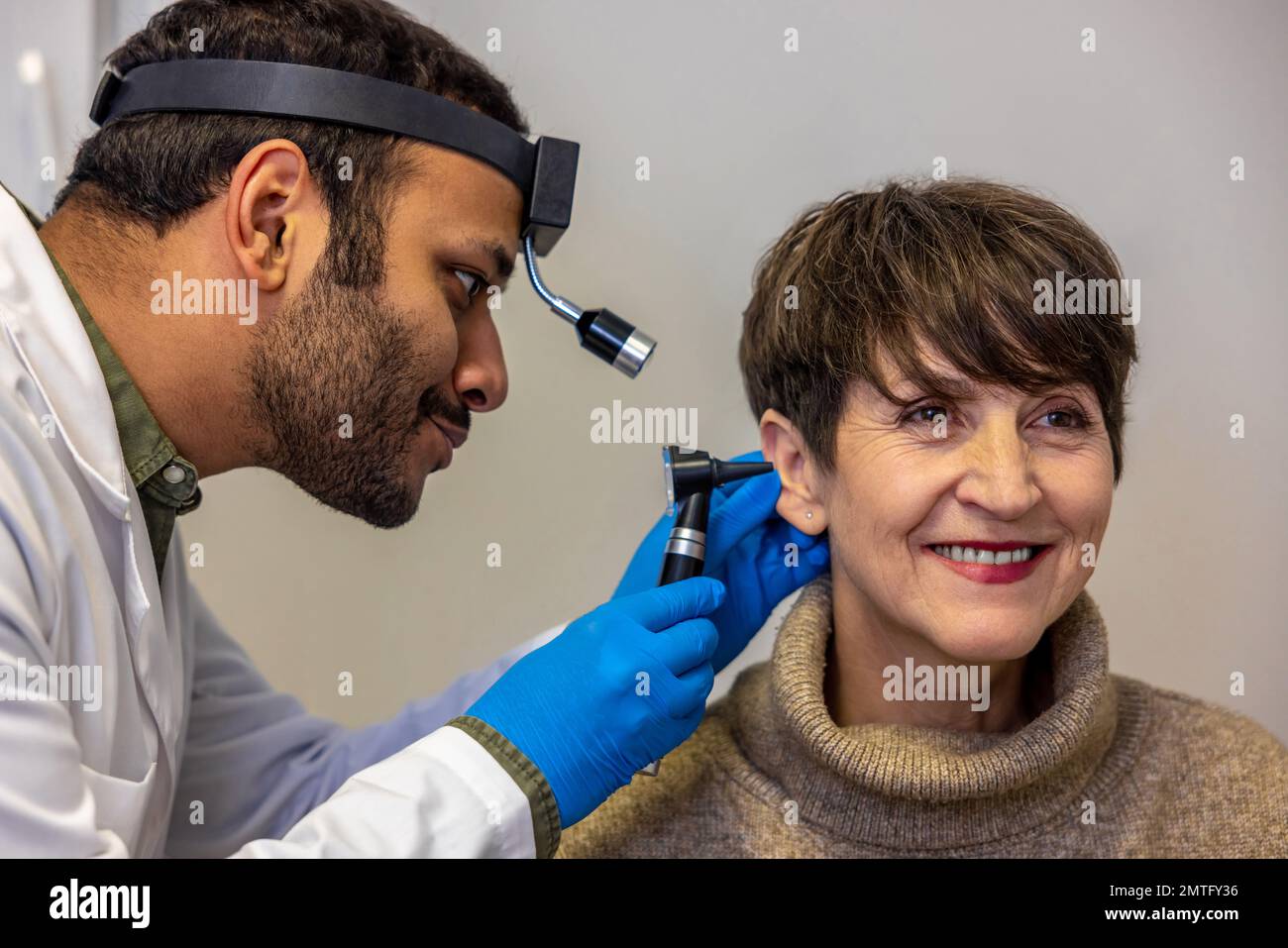 ENT doctor examinine patients ear with endoscope Stock Photo