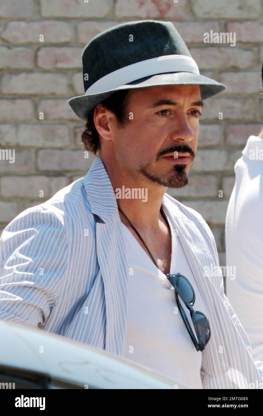 Wearing a black fedora and striped jacket with white pants and a t shirt,  actor Robert Downey Jr holds wife Susan's hand as the two leave Joel  Silver's Memorial Day party in