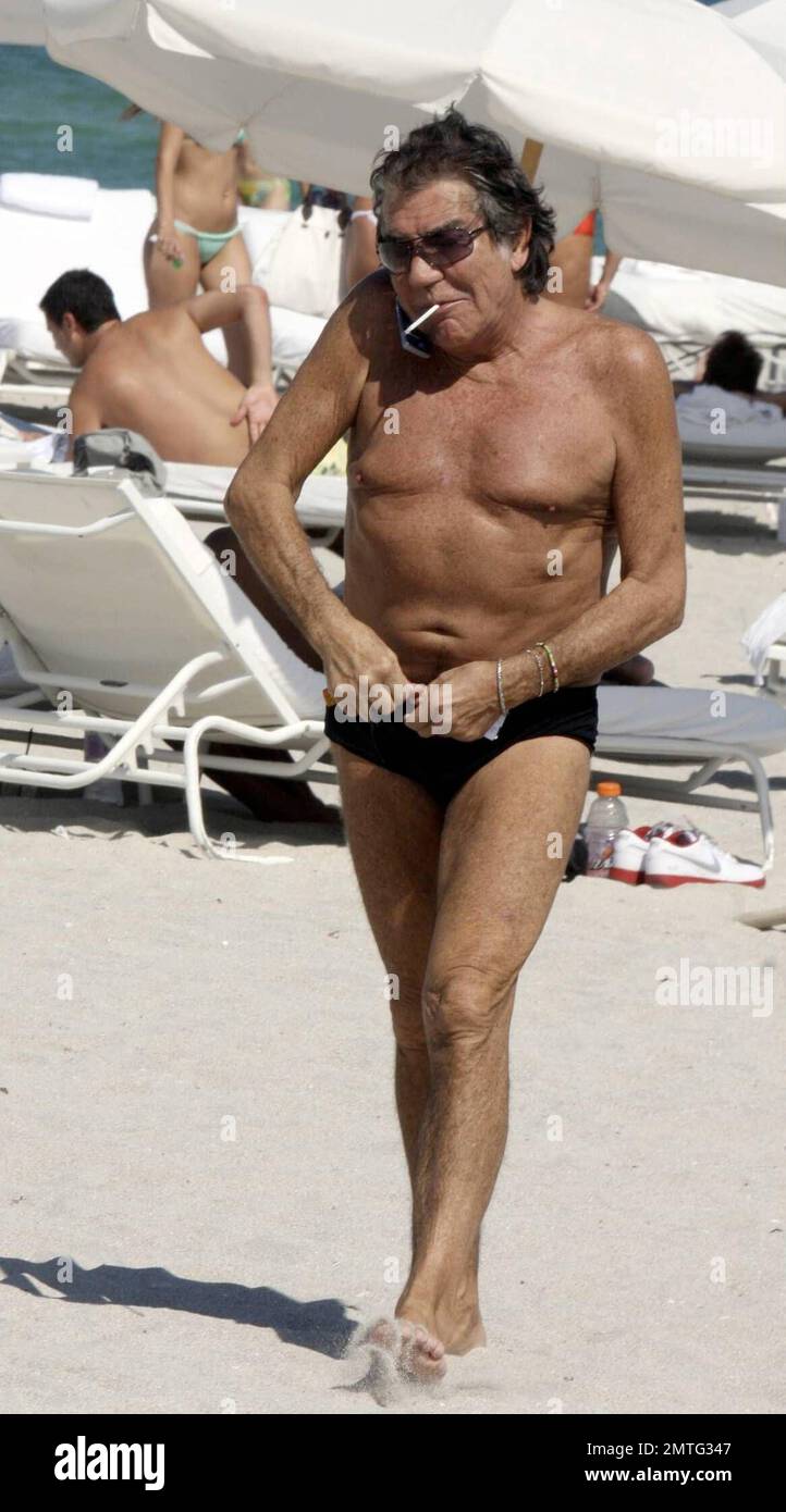 Fashion designer Roberto Cavalli, 67, spends a day on the beach soaking up  the South Florida sun with a young female companion. The pair strolled  together on the beach and relaxed on