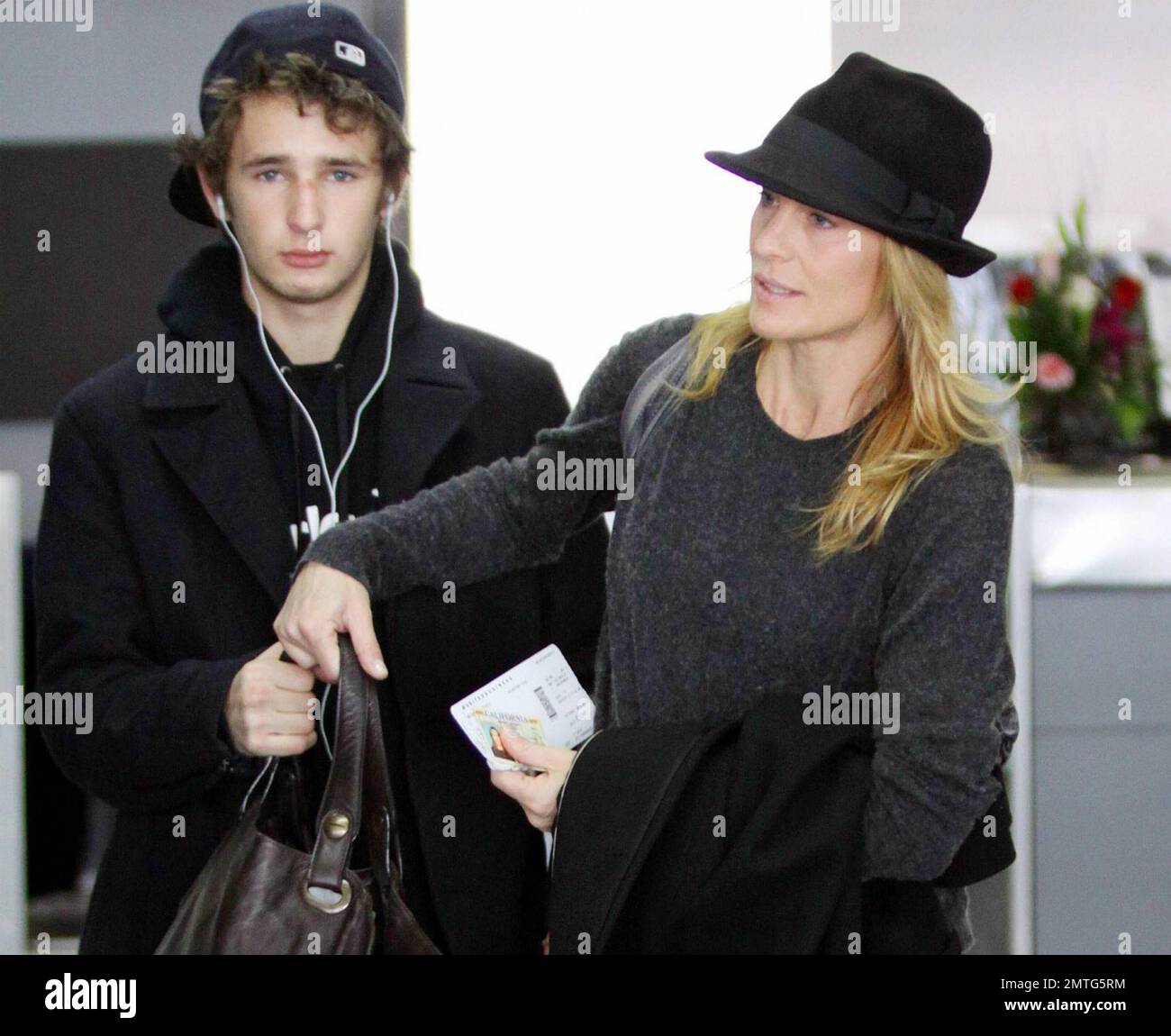 EXCLUSIVE!! Six months after her divorce from Oscar winning actor Sean Penn, actress Robin Wright, 44, makes her way through LAX with her son Hopper Penn, 18.  Despite not wearing makeup Wright's skin looked fresh and wrinkle free.  According to reports Robin received half of her ex's earnings in their divorce settlement, the news came after Sean reportedly mentioned that he 'had just got taken for one half of everything I had in the divorce' when speaking about his social work in Haiti. Los Angeles, CA. 01/08/11. Stock Photo