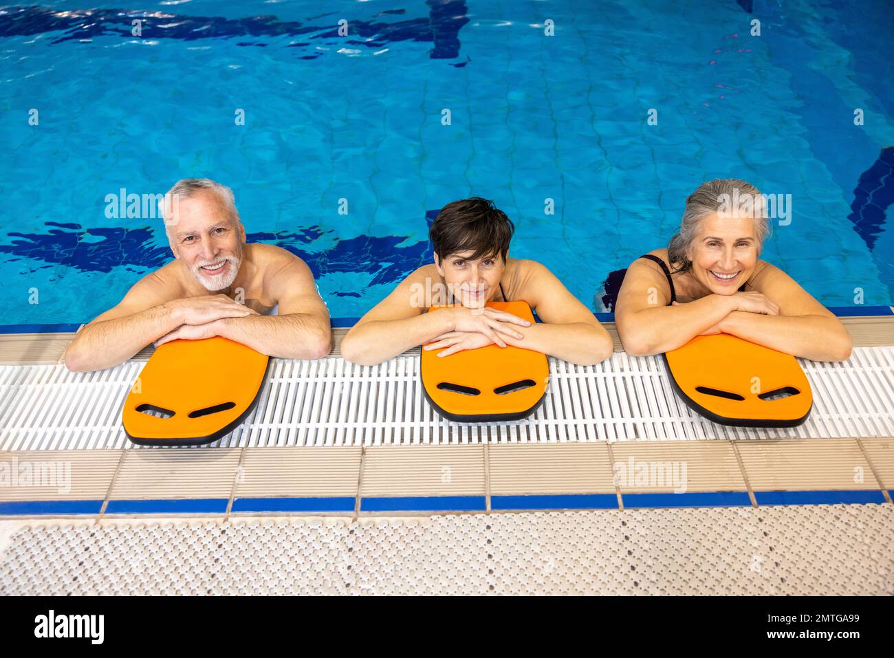 Group of senior swimmers resting on the pool side Stock Photo