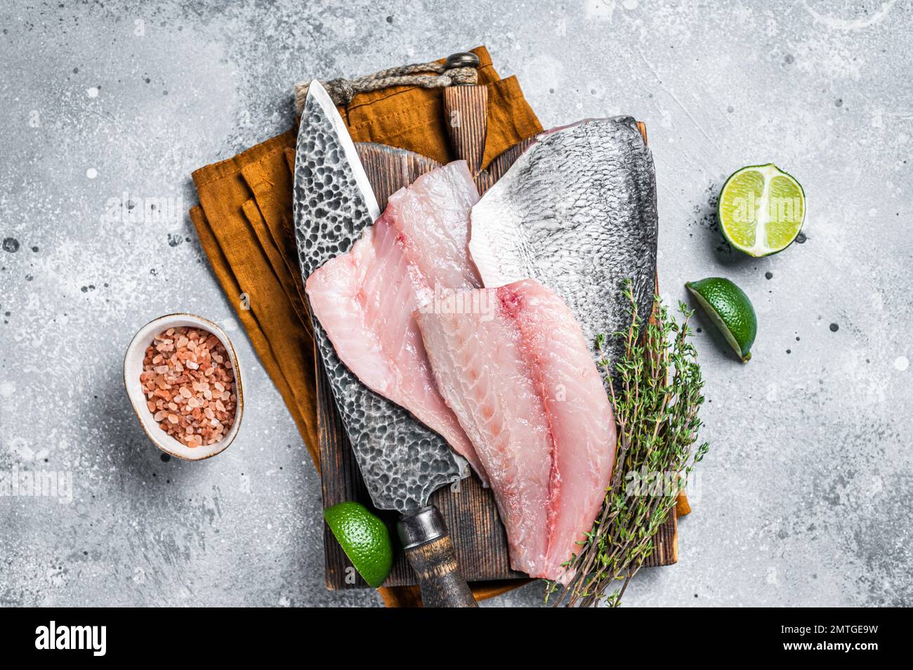 Raw Gilthead Sea bream fish fillets on a butcher cutting board. Gray ...