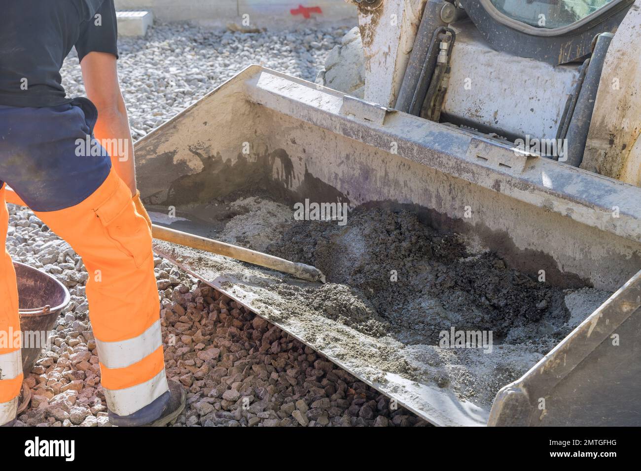 On construction site road workers knead cement mortar into buckets of an excavator Stock Photo