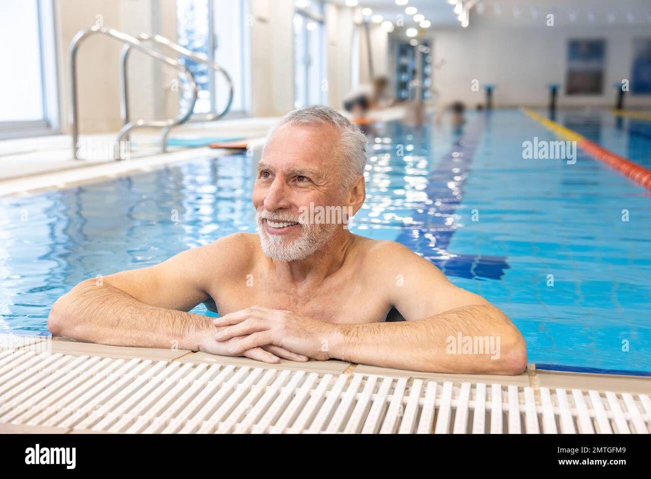 Gray-haired bearded swimmer looking contented at the swimming pool Stock Photo