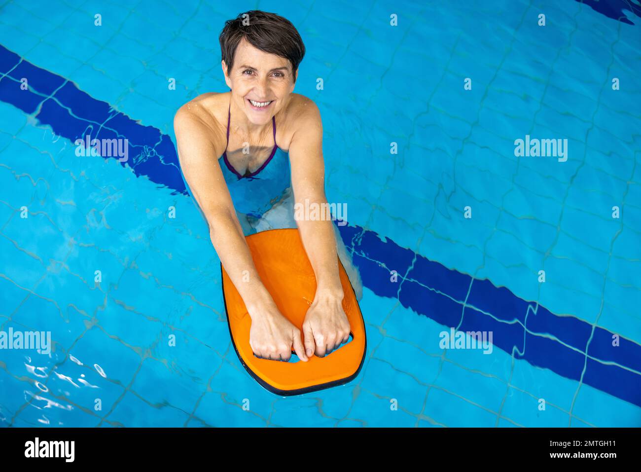 Short-haired smiling caucasian woman swimming in the swimming pool Stock Photo