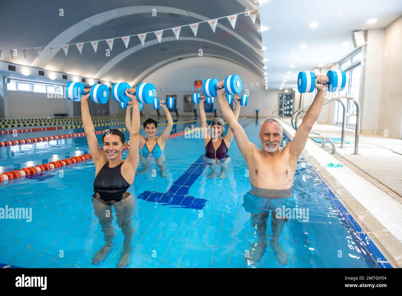 Young dark-haired coach leading a class of water aerobics Stock Photo