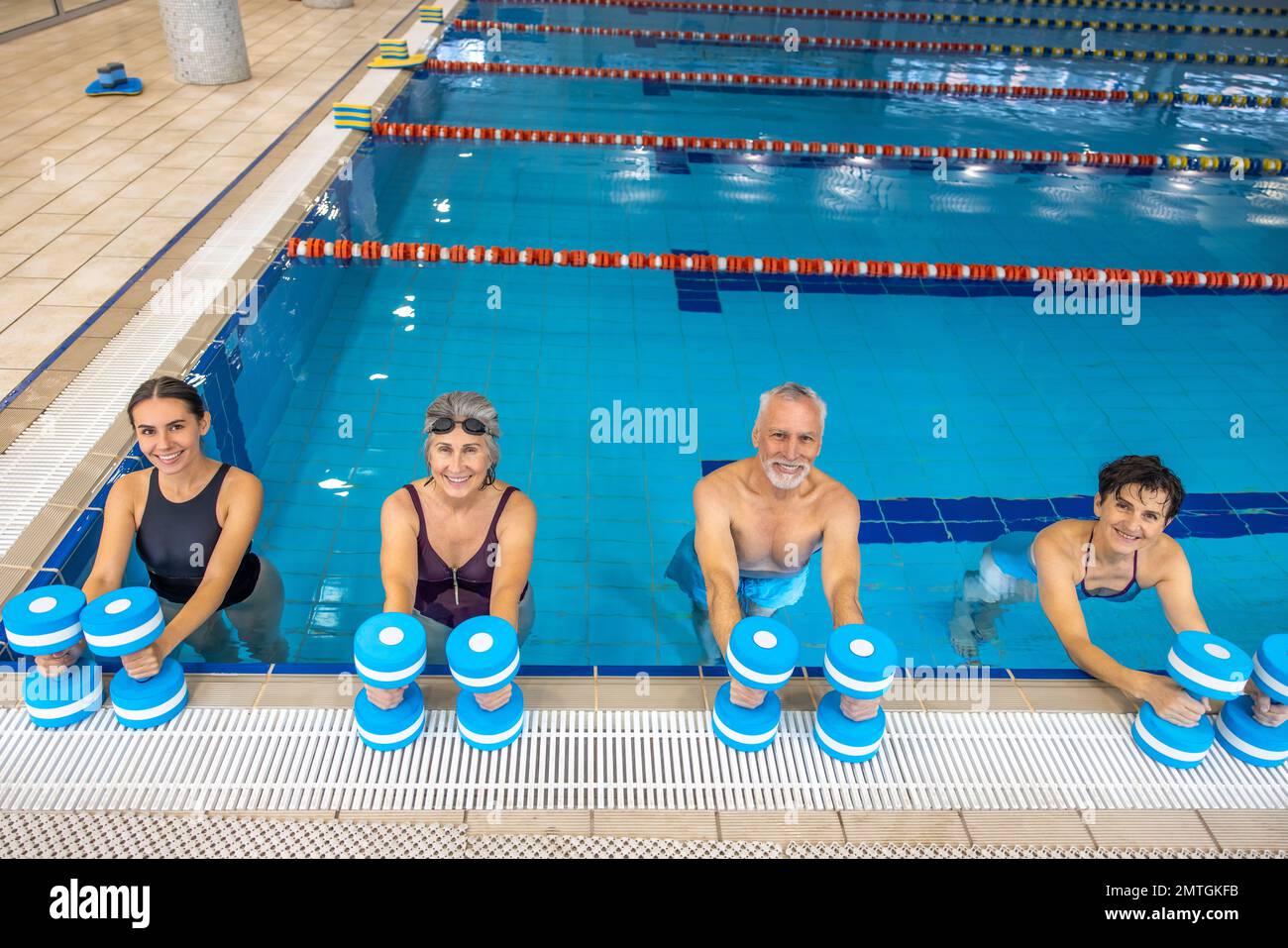 Group of seniors having an exercise with dumbbels during water aerobics class Stock Photo