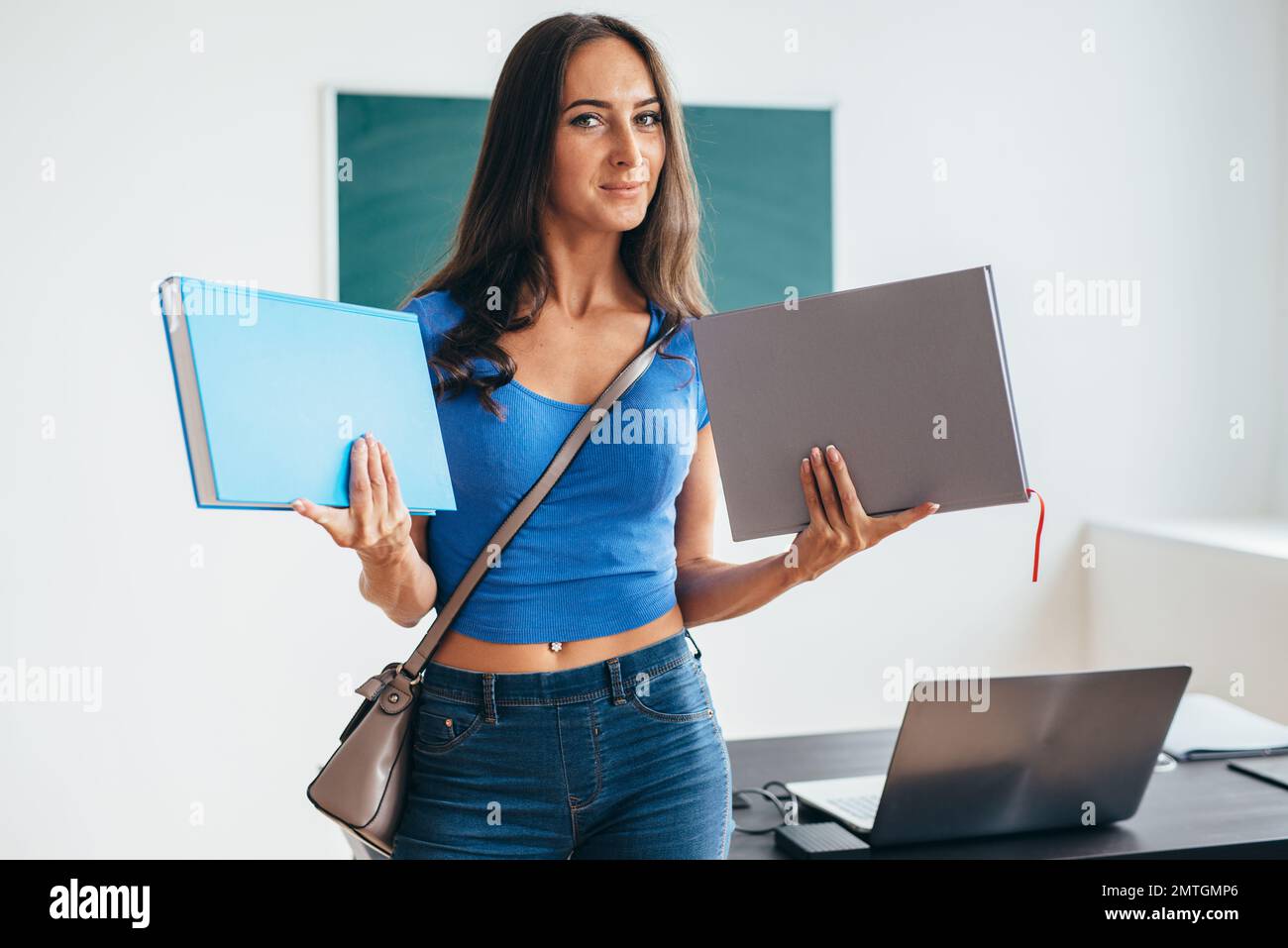 Female student in classroom holding book and smiling Stock Photo - Alamy