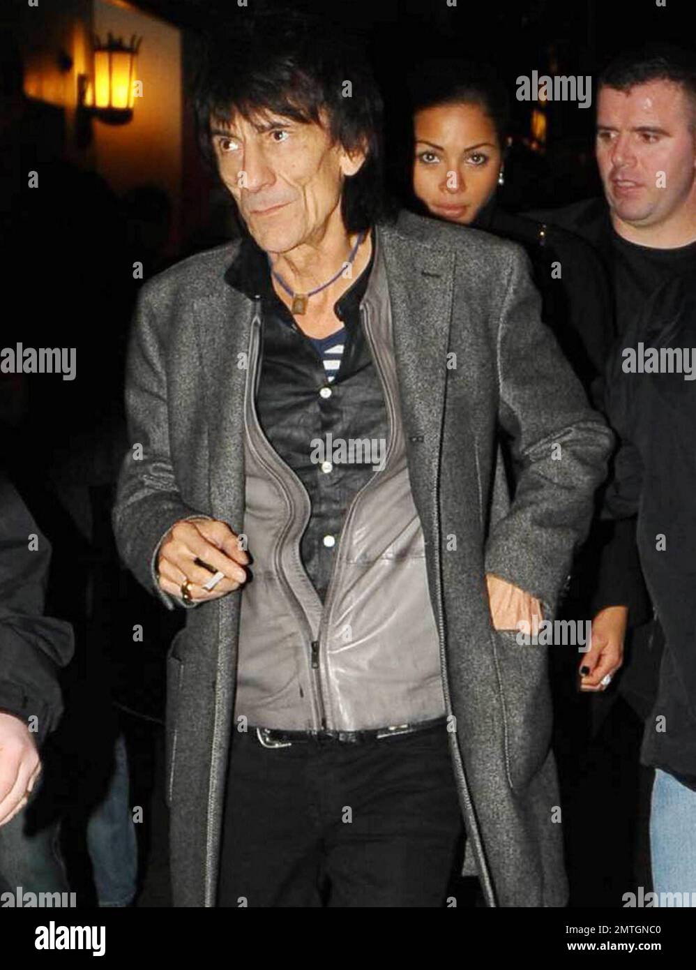 Sucking back on a cigarette and wearing white high-top sneakers The Rolling Stones guitarist Ronnie Wood and girlfriend, Brazilian polo coach Ana Araujo, are flanked by security guards as they arrive at the West End's Ambassadors Theatre for an intimate one-night only concert launching the tribute album Boogie 4 Stu.  The album was created by Ben Waters in memory of the late Ian Stewart (aka Stu), co-founder of The Rolling Stones, who died from a heart attack at the age of 47 in 1985.  Proceeds from the album will go to the British Heart Foundation.  As Ronnie made his way about the outside of Stock Photo