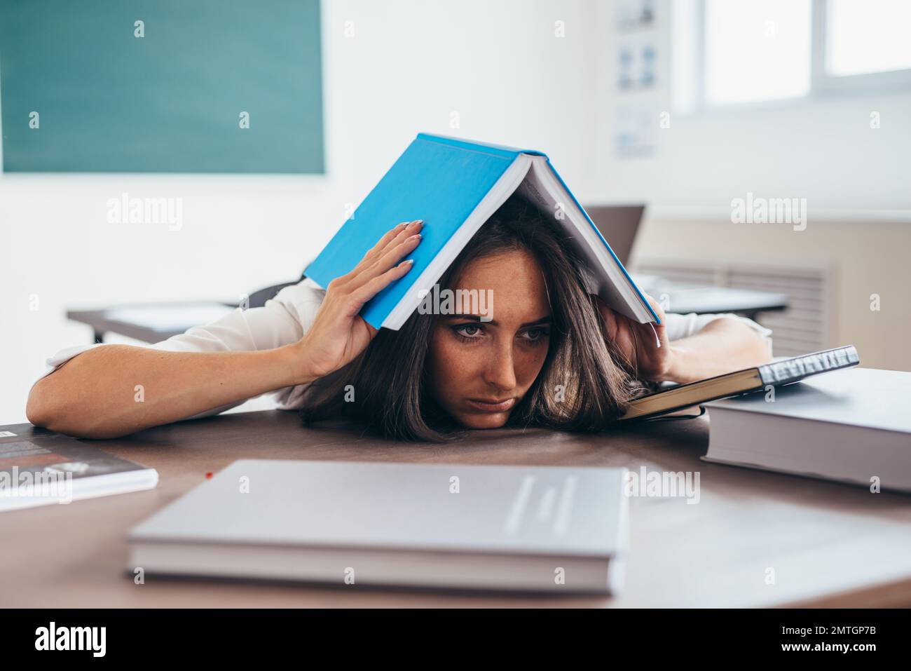 Tired young woman sleeping on desk with books Stock Photo - Alamy