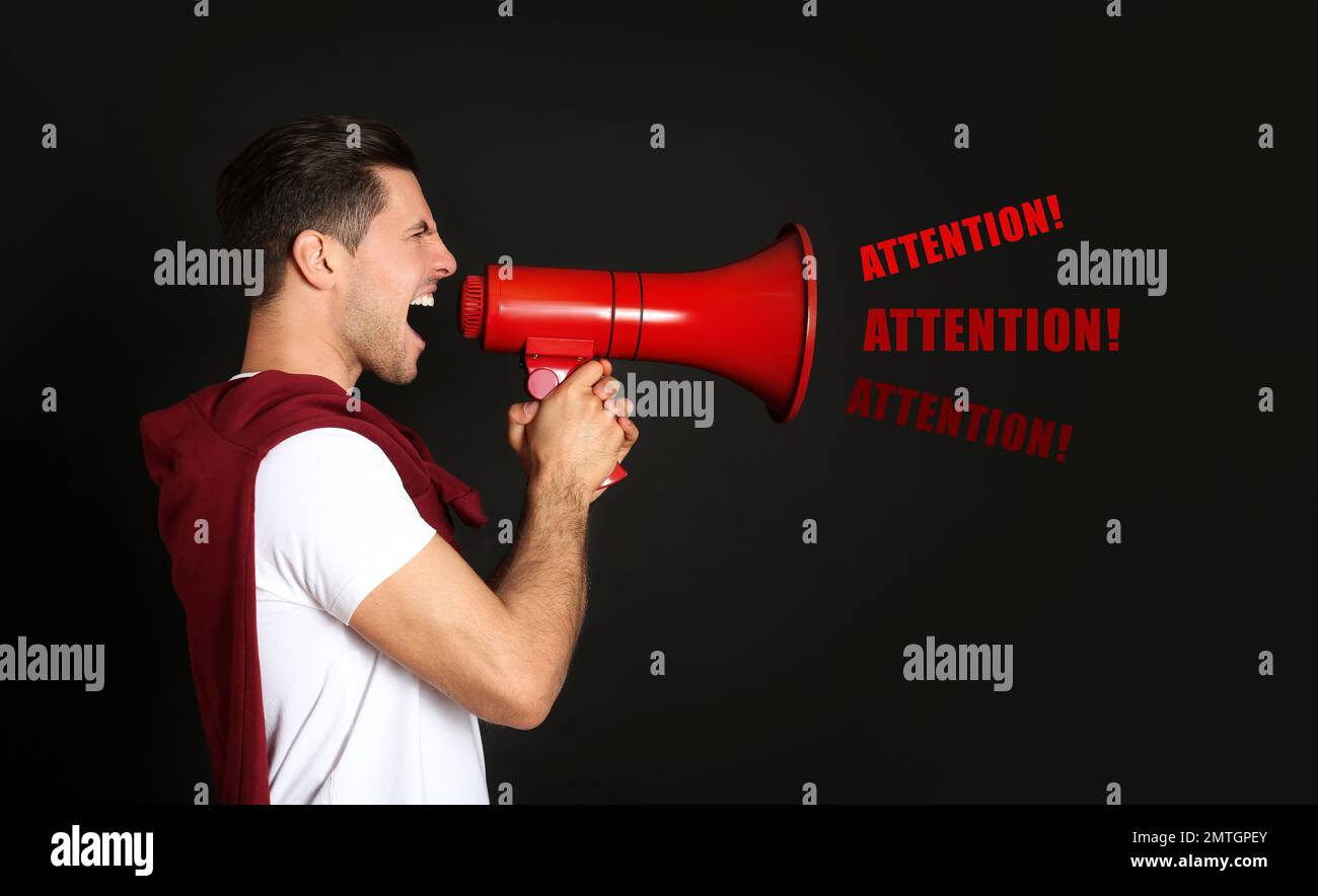 Handsome man with megaphone on black background Stock Photo
