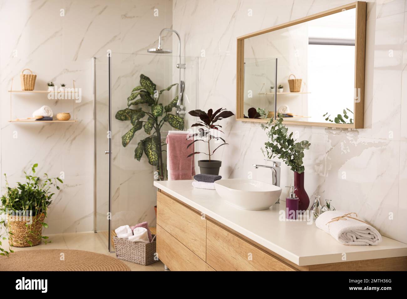 Stylish bathroom interior with countertop, shower stall and houseplants