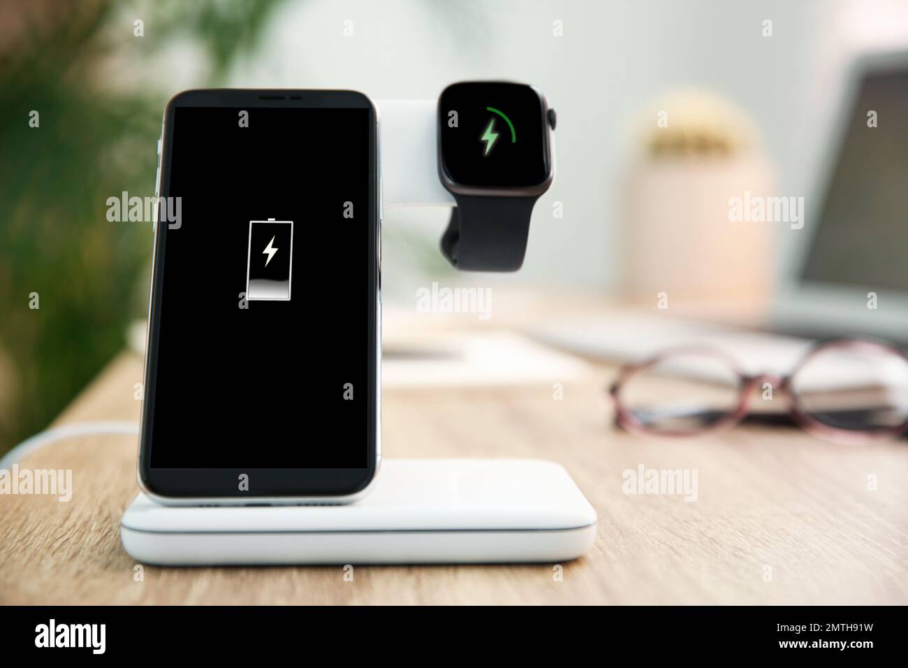 Mobile phone and smartwatch with wireless charger on wooden table ...