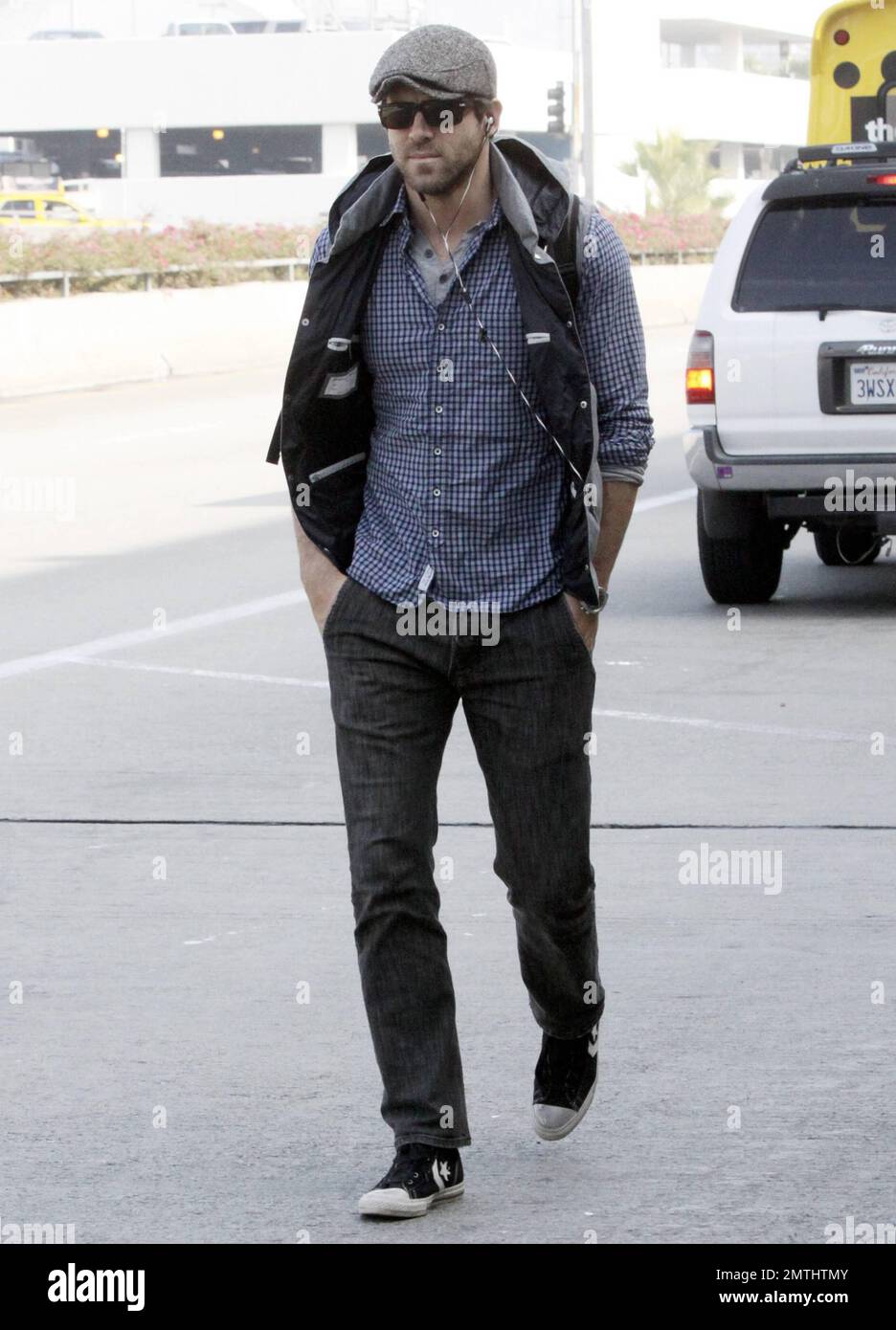 Actor Ryan Reynolds looks casual in a plaid shirt, grey hat and black vest  paired with jeans and black sneakers as he arrives at LAX after a flight  from New York amid
