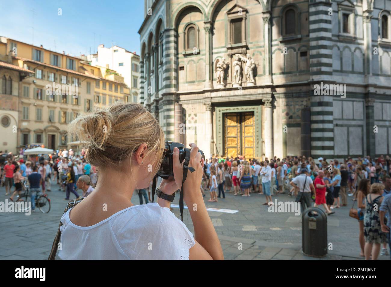 Female taking photo, rear view of a young woman with a camera taking a picture of the Renaissance-era Baptistry building in Florence, Italy Stock Photo