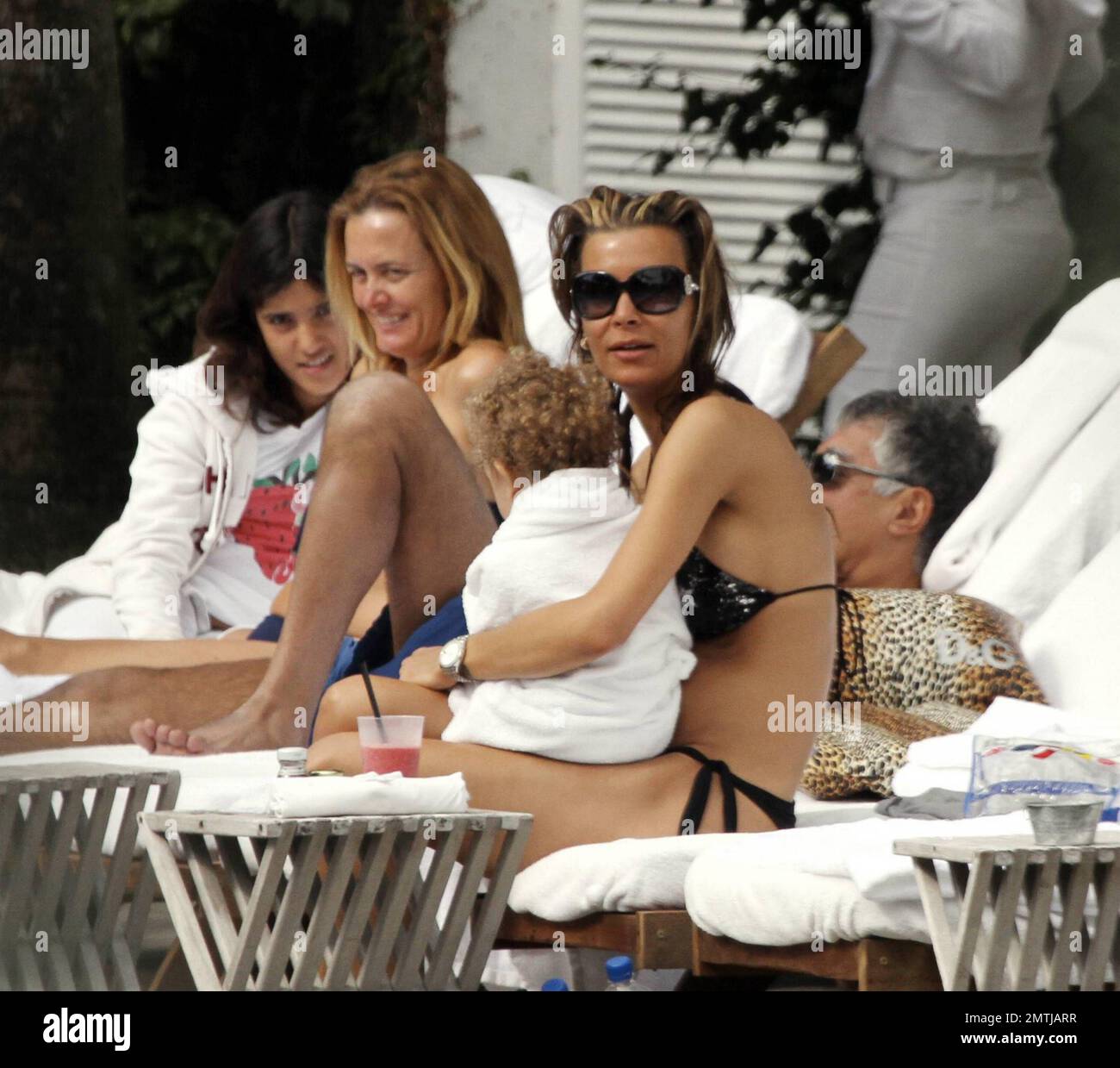 Tattooed Beauty Queen, Sarah Gerth, wife of German footballer Jermaine Jones, relaxes poolside at her luxury hotel in a star string bikini. The blonde beauty also got a cuddle from one of her twins and lounged with her own animal print designer Dolce & Gabbana pillows. Miami Beach, FL. 12/29/10. Stock Photo