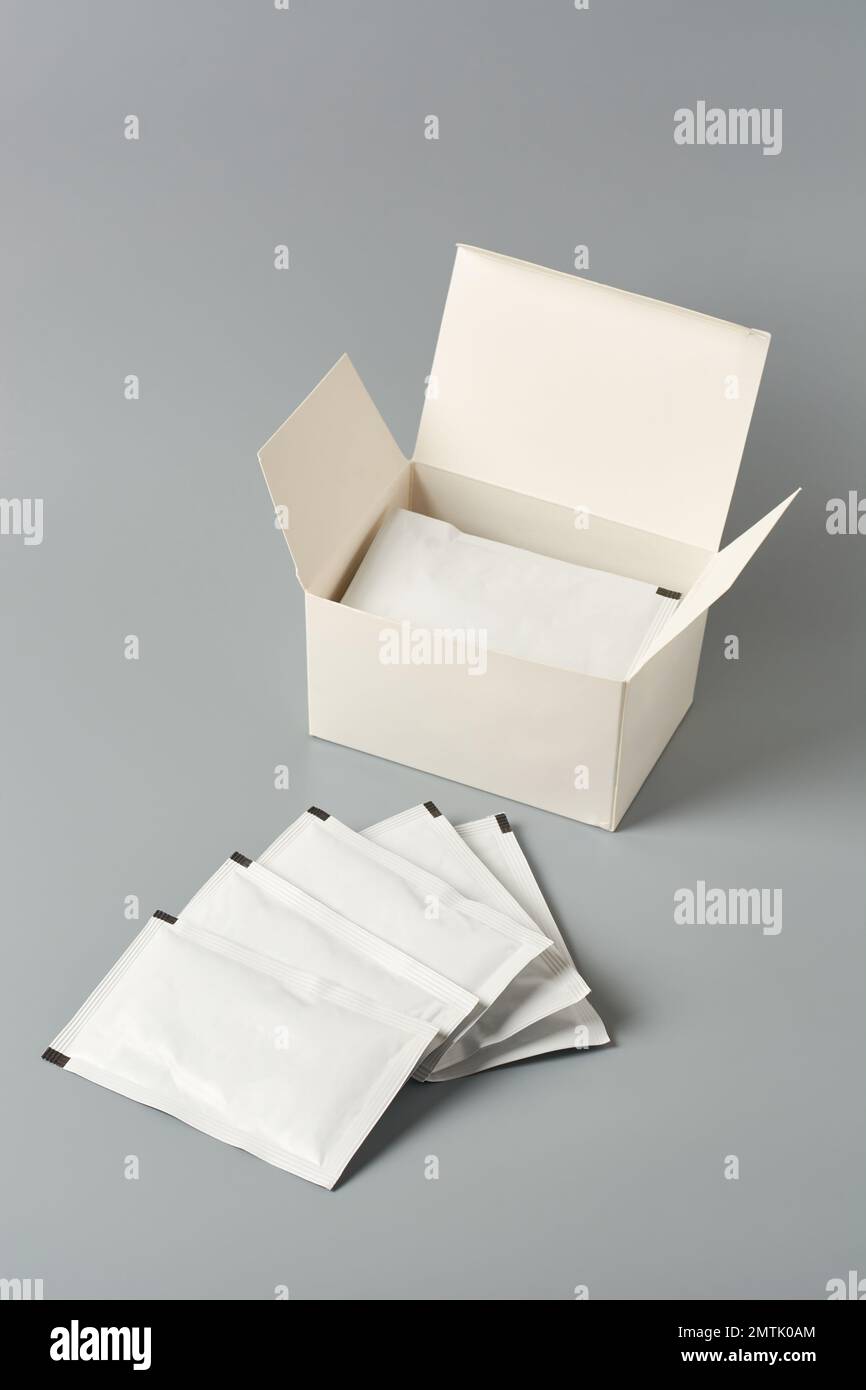 blank white sachet packets and with a blank box isolated on neutral gray background, food or medicine drug packaging mockup template Stock Photo